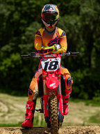 Motocross rider sitting on a red Honda dirt bike with racing number 18, wearing Alpinestars 2025 Supertech Lipan Jersey and matching pants in Yellow and Pink, bright pink Alpinestars boots, Red Bull helmet, professional racing gear for off-road performance.
