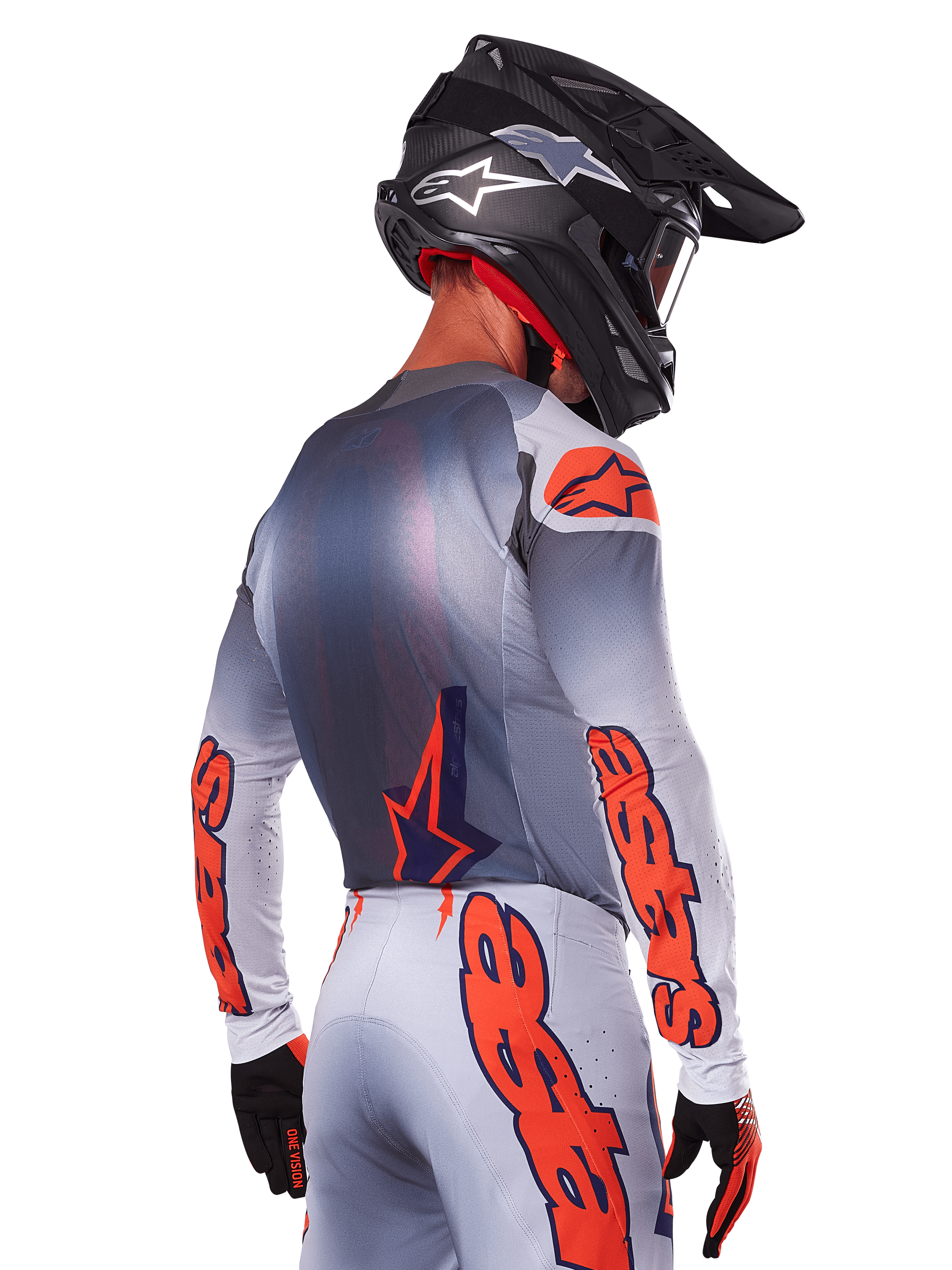Motocross-Fahrer von hinten im Alpinestars 2025 Supertech Lipan Jersey in Grau Orange Fluo, mit markanten orangefarbenen Logos auf den Ärmeln und dem Rücken, kombiniert mit passender Hose und schwarzem Helm, professionelles Rennoutfit für Offroad-Performance.