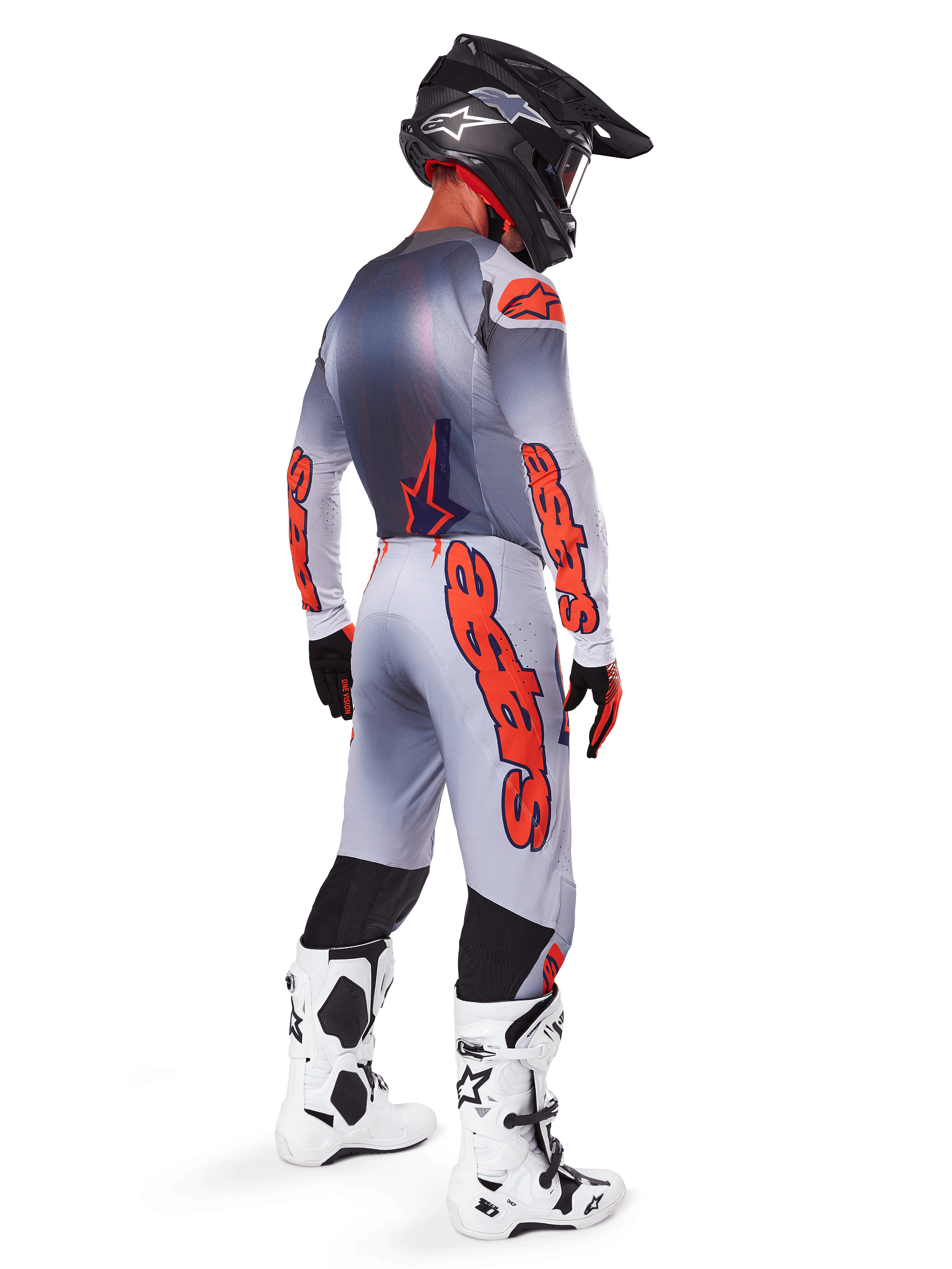 Motocross rider from behind wearing the 2025 Supertech Lipan Gear Set, Gray and Orange Fluo jersey with matching pants, bold orange Alpinestars branding on sleeves and legs, black helmet, white and black motocross boots, coordinated professional off-road racing outfit.