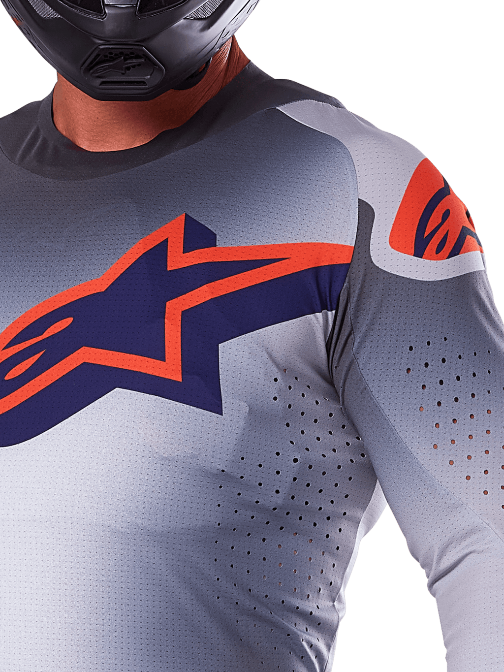 Nahaufnahme eines Fahrers im Alpinestars 2025 Supertech Lipan Trikot, Motocross-Trikot, Grau und Orange Fluo, mit einem großen orangen Alpinestars-Logo auf der Brust, lasergeschnittenen Belüftungsöffnungen und einem schwarzen Helm, professionelle Rennausrüstung.