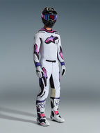 Motocross-Fahrer im Alpinestars 2026 Supertech AFD Vista Trikot in Weiß Lila Schwarz, passende Motocross-Hose mit pink-lila Logos im Farbverlauf, schwarzer Helm mit lila Brille, weiß-schwarze Stiefel und weiße Handschuhe, komplettes professionelles Offroad-Rennsport-Set