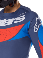 Close-up of Alpinestars 2025 Techstar Dreem Jersey, navy blue with vibrant blue and orange accents, white Alpinestars branding on chest and shoulder, featuring laser-cut perforations for ventilation