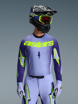 Alpinestars 2026 Supertech Scenz Jersey, Motocross Jersey, Purple and Yellow Fluo, worn by a rider with a matching black and purple helmet, neon yellow goggles, and purple racing pants, featuring neon yellow astars branding on the chest and star logos on the sleeves.