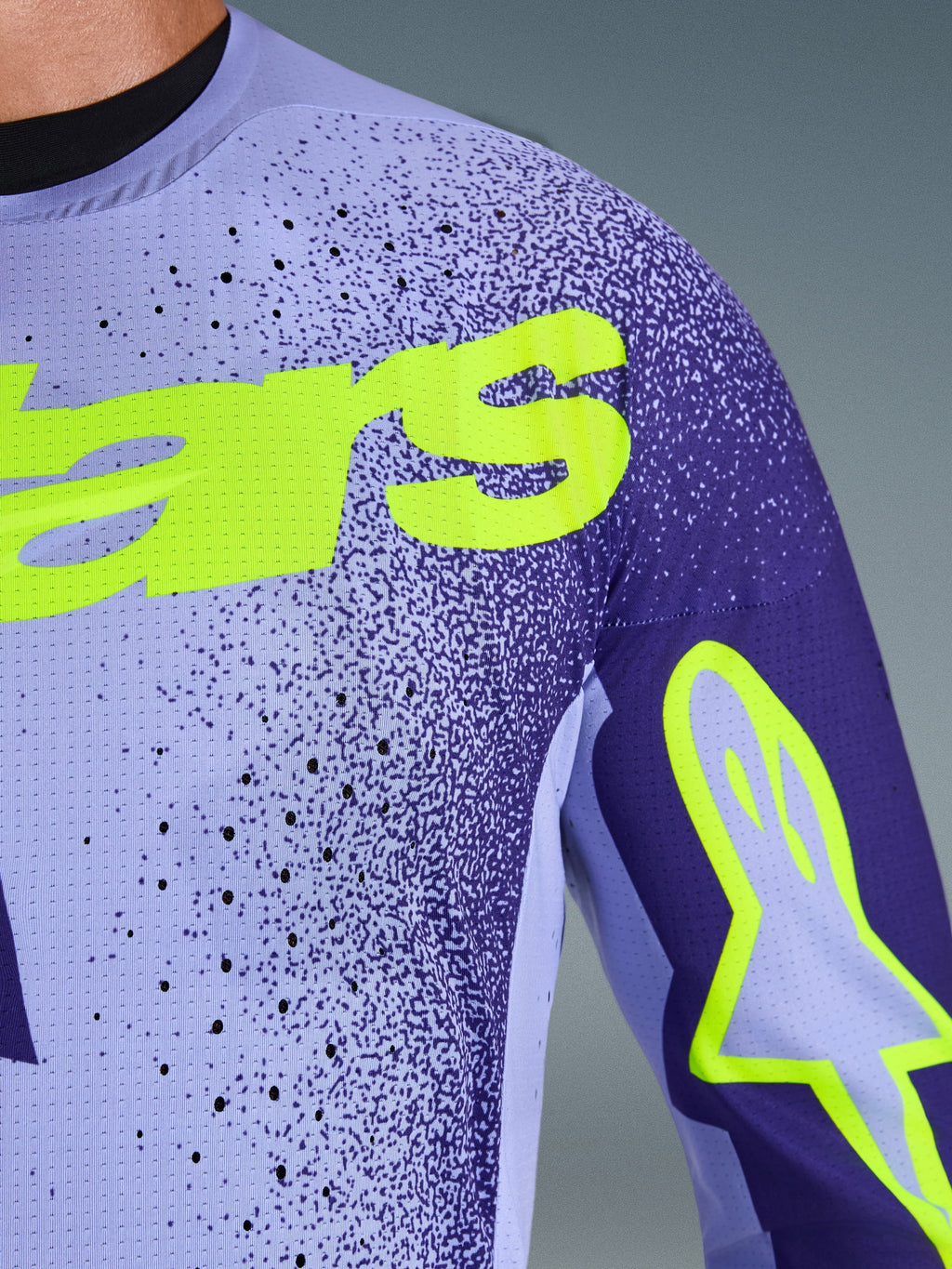 Alpinestars 2026 Supertech Scenz Jersey, Motocross-Trikot, Lila und Gelb Fluo, Nahaufnahme mit perforiertem Stretch-Mesh-Material und leuchtend gelbem Alpinestars-Branding auf der Brust und am Ärmel