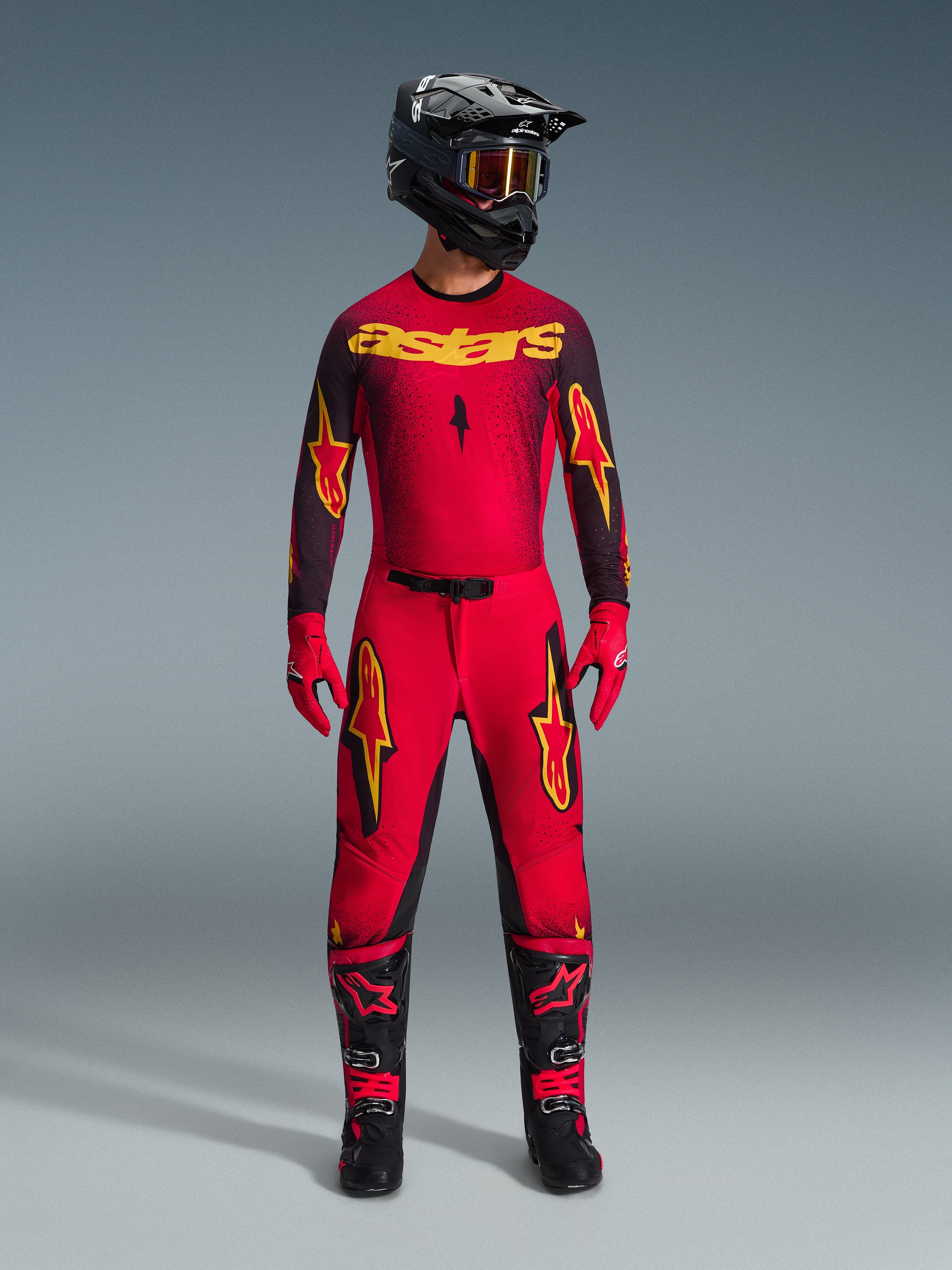 Alpinestars 2026 Supertech Scenz Gear Set, komplette Motocross-Rennausrüstung in Rot und Schwarz mit gelben Grafiken, bestehend aus Profi-Jersey und passender Hose, getragen mit schwarzem Helm, roten Handschuhen und schwarzen Rennstiefeln, hochwertige Performance-Ausrüstung für den Offroad-Wettbewerb