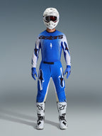 Motocross-Fahrer im Alpinestars 2026 Supertech Scenz Gear Set in Ucla Blau und Weiß, mit einem leichten blau-weißen Trikot mit schwarzem Branding, passender blauer Hose, weißem Rennhelm und weißen Motocross-Stiefeln, Pro-Level-Performance-Ausrüstung für den Offroad-Rennsport.
