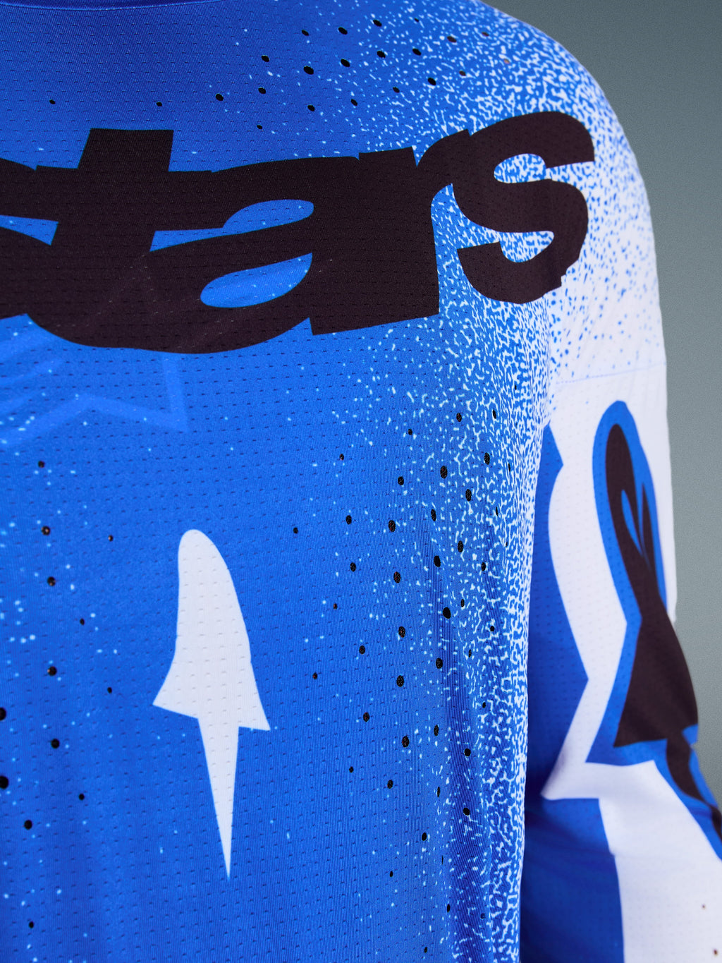 Alpinestars 2026 Supertech Scenz Trikot, Nahaufnahme des Designs in Ucla Blau und Weiß, mit lasergeschnittenen Perforationen zur Belüftung, schwarzem 'stars' Branding und atmungsaktivem Mesh-Gewebe für professionellen Motocross-Rennsport.