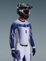 Motocross-Fahrer im 2026 Supertech Scenz Trikot in Hellgrau und Dunkelblau, kombiniert mit einer passenden weiß-blauen Rennsporthose, blauen Handschuhen und einem schwarzen Helm mit weißer Brille. Das Trikot verfügt über einen gepunkteten blauen Farbverlauf auf der Brust und den Ärmeln, eine professionelle athletische Passform und ein markantes „astars“-Branding.