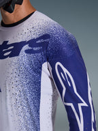 Nahaufnahme des Alpinestars 2026 Supertech Scenz Trikots in Hellgrau und Dunkelblau, mit lasergeschnittenen Perforationen, gesprenkeltem Grafikmuster, weißem Astars-Logo auf dem Ärmel, professionelle Motocross-Performance-Passform