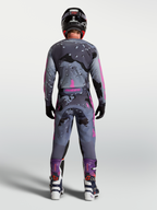 Alpinestars Racer Lone Hose, Motocross-Ausrüstung für Herren, Grau Camo und Lila, strapazierfähige Motocrosshose im Race-Fit, Rückansicht des Fahrers mit Helm und Stiefeln.