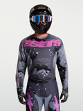 Alpinestars Racer Lone Trikot, Motocross-Trikot für Herren, Grau und Lila Camo-Design, am Model mit Helm.