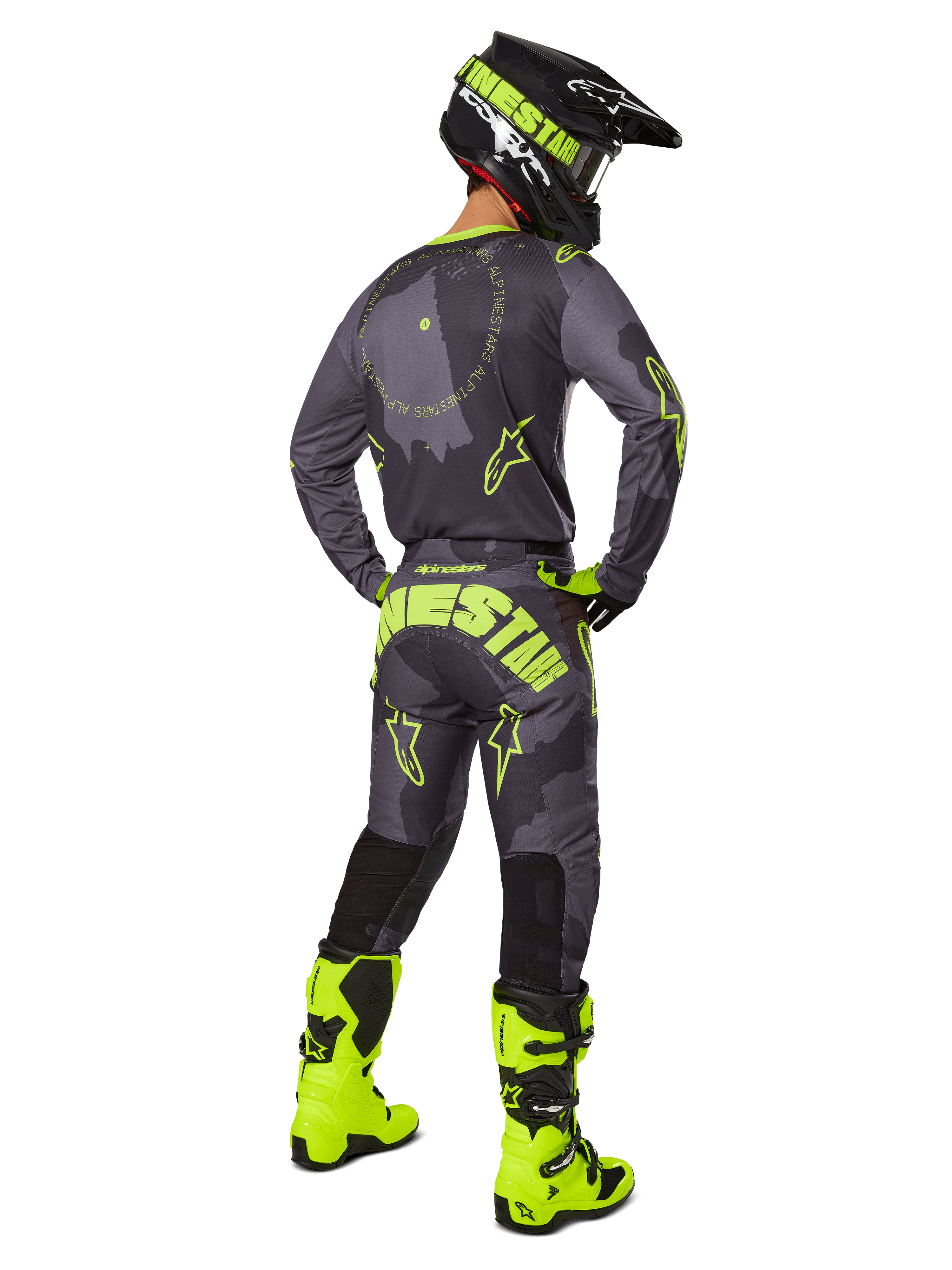 Rückansicht eines Motocross-Fahrers im 2025 Racer Hollow Gear Set in Dark Camo Yellow Fluo, bestehend aus einem grauen Camo-Trikot mit gelben Fluo-Akzenten, der passenden Motocross-Hose mit markantem Branding am Gesäß, leuchtend gelben Fluo-Stiefeln und einem schwarzen Helm mit gelber Brille.