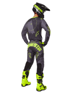 Motocross rider from the back wearing the Alpinestars 2025 Racer Hollow Jersey and Pants in Dark Camo Yellow Fluo, featuring a dark grey camo pattern with neon yellow accents, paired with a matching black and yellow helmet and bright neon yellow boots.