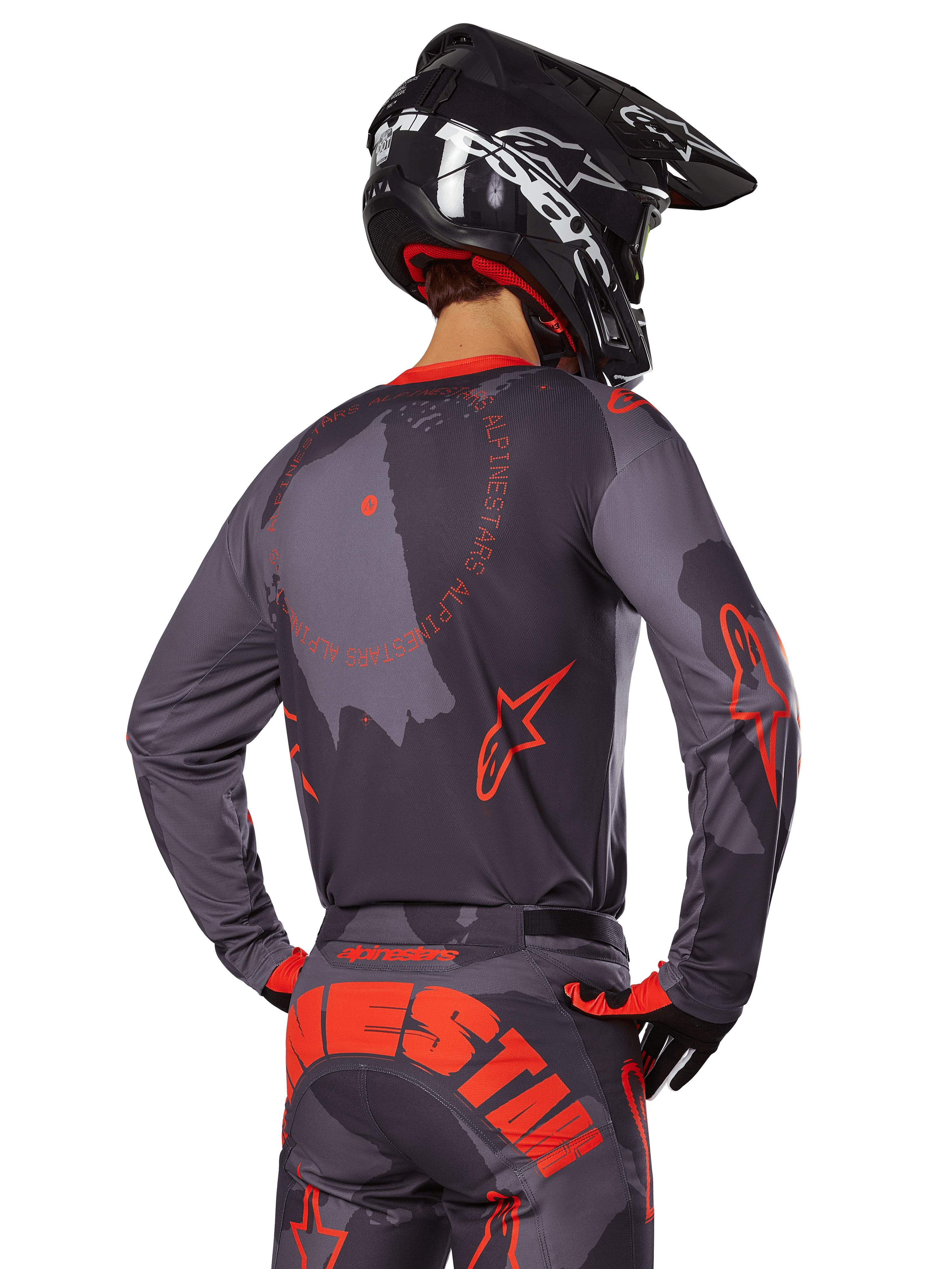 Alpinestars 2025 Racer Hollow Trikot, Rückansicht eines Motocross-Fahrers in Grau Camo und Orange Fluo Ausrüstung, mit passender Camo-Hose mit großem orangefarbenem Alpinestars-Schriftzug und einem schwarzen Helm, professionelles Offroad-Bekleidungsdesign