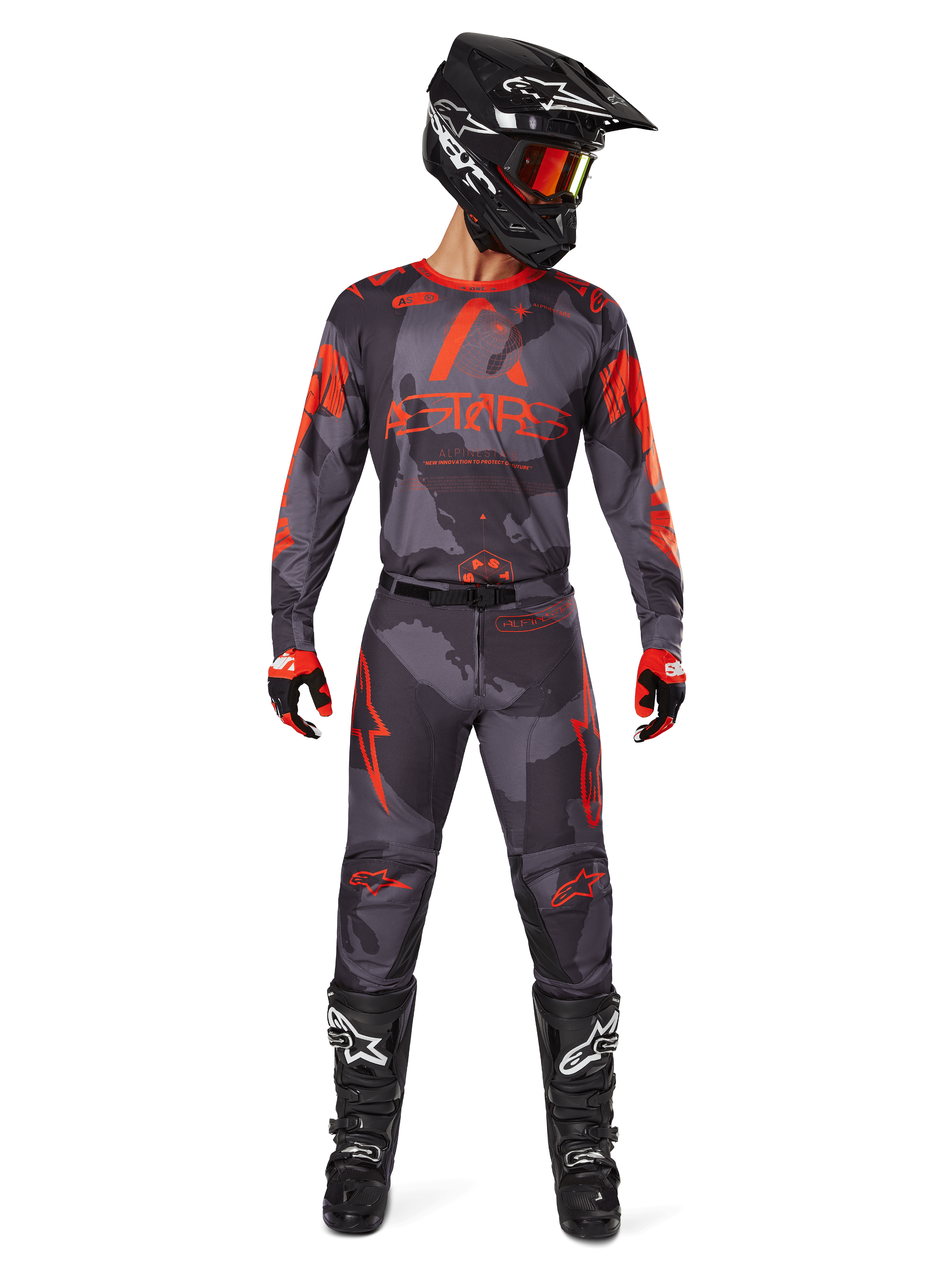 Motocross-Fahrer mit Alpinestars 2025 Racer Hollow Trikot und passender Hose in Grau Camo Orange Fluo, komplette Ausrüstung mit schwarzem Helm, Goggles, Handschuhen und Stiefeln, markante orangefarbene Logos und Camouflage-Muster.