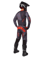 Motocross-Fahrer in der Rückansicht, Alpinestars 2025 Racer Hollow Trikot in Gray Camo Orange Fluo, passende Camo-Hose mit orangem Alpinestars-Schriftzug, schwarzer Helm und schwarze Stiefel, abgestimmtes Ausrüstungsset für Offroad-Fahrten