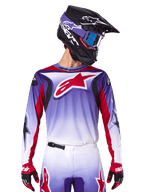 Alpinestars 2025 Fluid Wurx Trikot, Motocross-Rennsport-Trikot, lila-weißer Farbverlauf, rotes Sternenlogo und Akzente, athletische Passform, getragen mit passender Hose, schwarzem Helm und roten Handschuhen