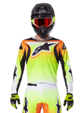 Alpinestars 2025 Fluid Wurx Trikot, Motocross-Trikot, Neongelb, Orange und Weiß, getragen mit passender Hose und schwarzem Helm mit roter Brille, komplette MX-Ausrüstung am Fahrer
