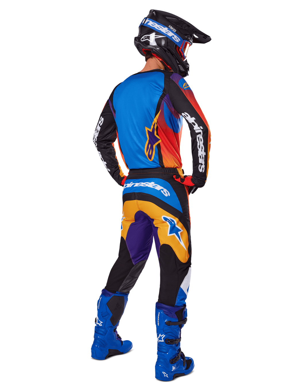 Motocross-Fahrer in der Rückansicht mit Alpinestars 2025 Fluid Wurx Gear Set, mehrfarbiges Trikot mit blauen, orangefarbenen und lila Paneelen, passende Hose mit weißem Alpinestars-Logo auf dem Gesäß, leuchtend blaue Stiefel und schwarzer Helm, koordiniertes Outfit für den Offroad-Rennsport