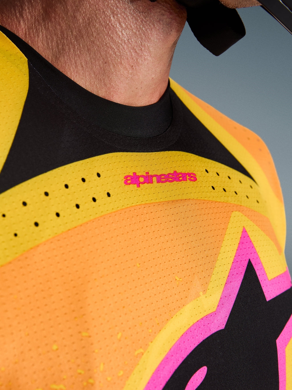 Alpinestars 2026 Techstar Nomur Trikot, Motocross-Trikot, Orange Gelb Pink, Nahaufnahme von Brust und Kragen mit lasergeschnittener Belüftung, pinkfarbenem Branding und atmungsaktivem Mesh-Gewebe