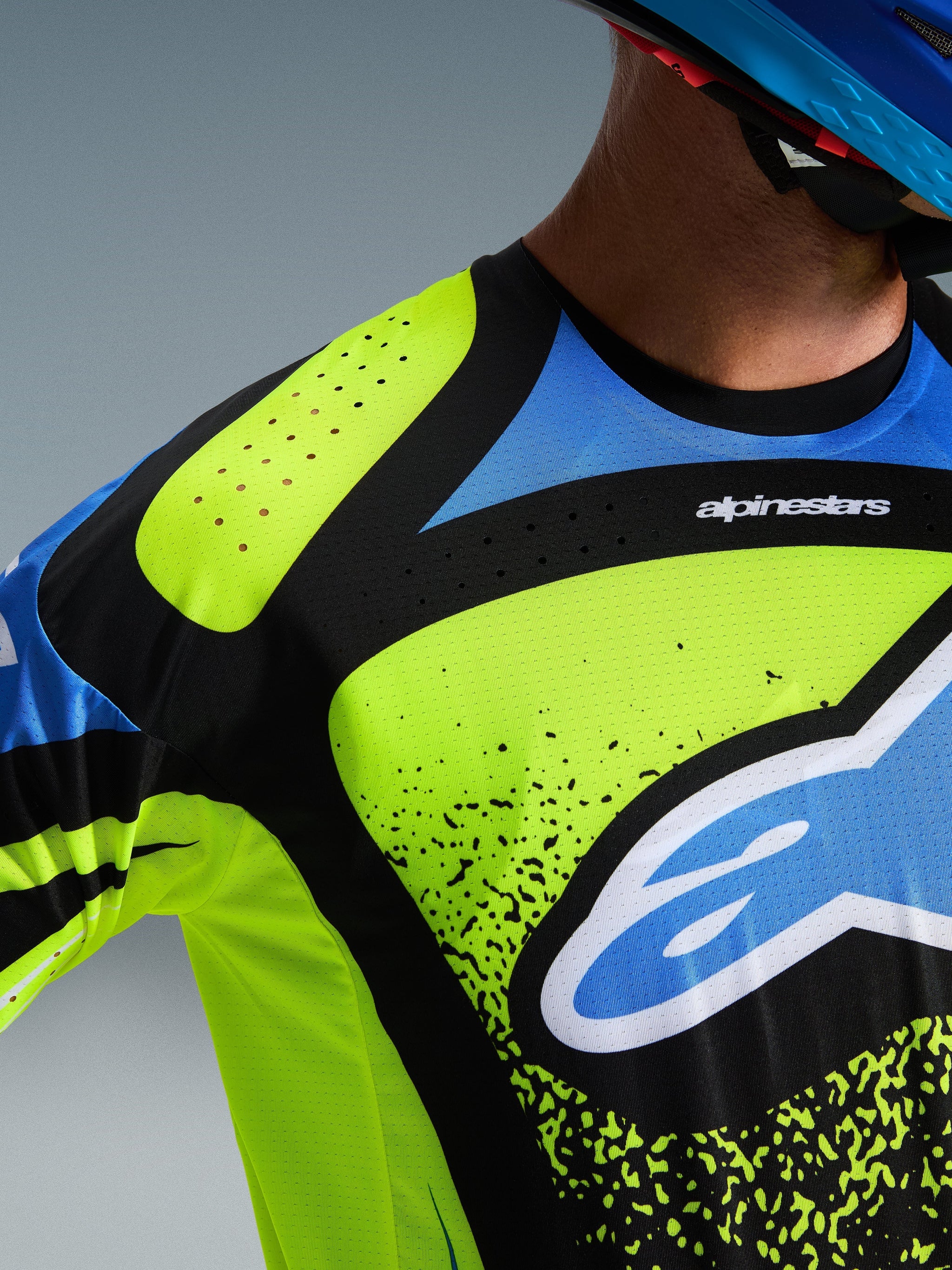 Alpinestars 2026 Techstar Nomur Trikot, Motocross-Trikot, Yellow Fluo, Dark Navy und UCLA Blue, Nahaufnahme von Brust und Schulter mit lasergeschnittenen Perforationen zur Belüftung und dem Alpinestars-Logo, Hochleistungs-Offroad-Rennausrüstung