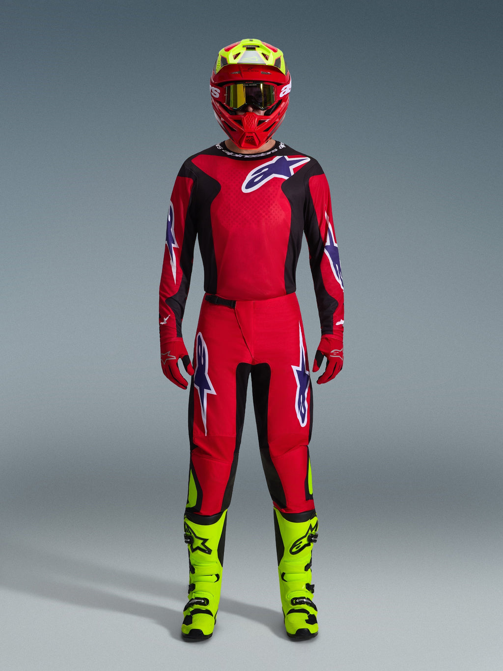 Motocross-Fahrer im 2026 Fluid Grid Trikot in Rot Schwarz Lila, passende rote Hose mit lila Logos, roter Helm mit neongelben Akzenten, neongelbe Stiefel, komplette abgestimmte Rennausrüstung für Offroad-Motocross