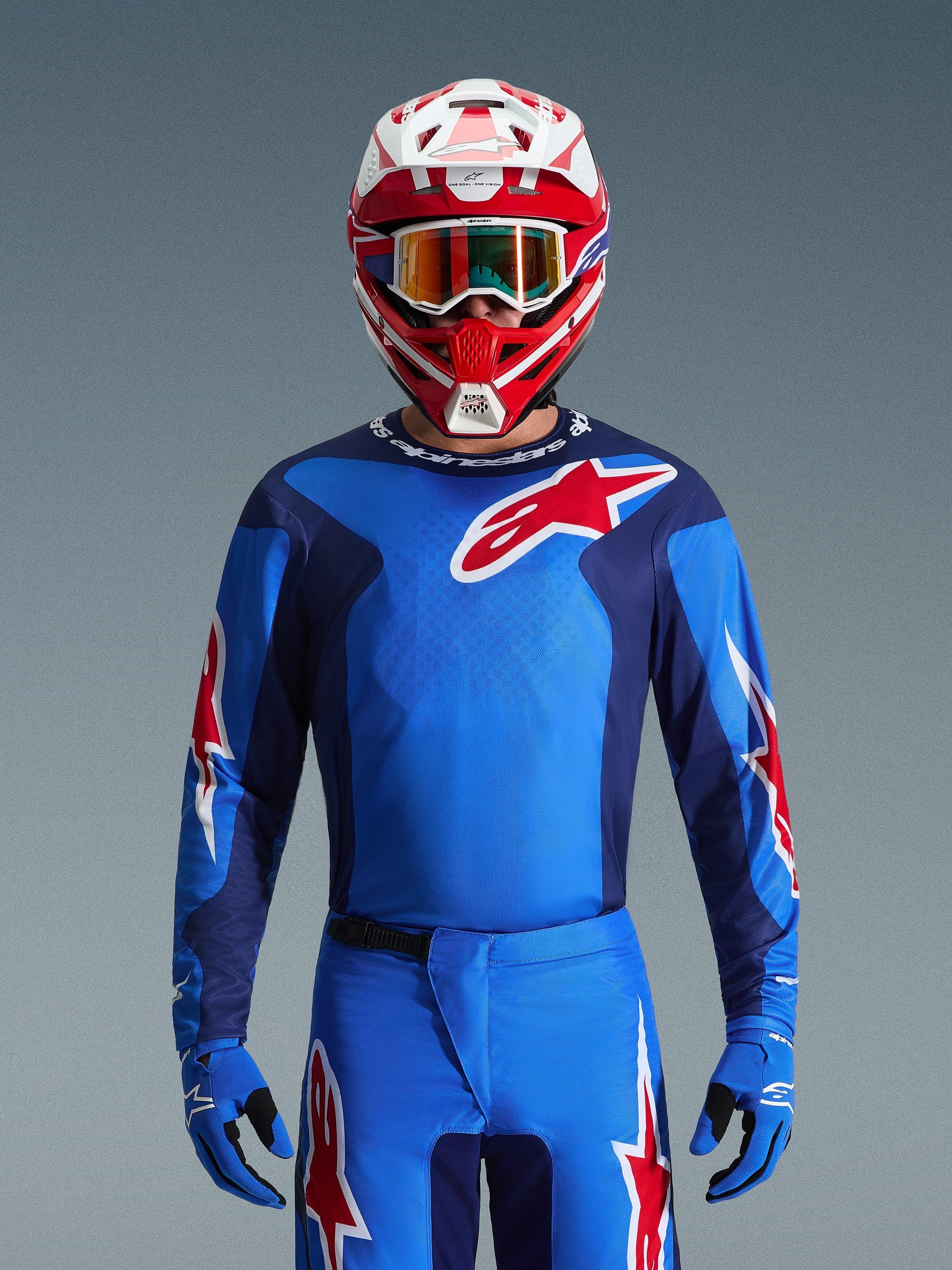 Alpinestars 2026 Fluid Grid Trikot, blau-rotes Motocross-Trikot, getragen mit passender Hose und einem rot-weißen Helm, mit markanten roten Stern-Logos und einer athletischen Passform für Performance im Offroad-Rennsport