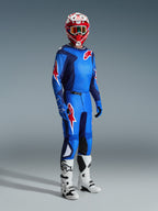 Motocross-Fahrer im Alpinestars 2026 Fluid Grid Trikot in Blau-Rot, kombiniert mit der passenden Motocross-Hose, weiß-schwarzen Stiefeln und einem rot-weißen Helm, professionelles Ausrüstungsset für Offroad-Performance.