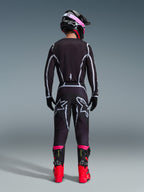 Motocross-Fahrer in Rückansicht, trägt das Alpinestars 2026 Fluid Apex Trikot und die passende Hose in Schwarz/Grau, mit weißen geometrischen Designlinien und Stern-Logos am Gesäß, kombiniert mit einem schwarz-pinken Helm und rot-schwarzen Rennstiefeln.