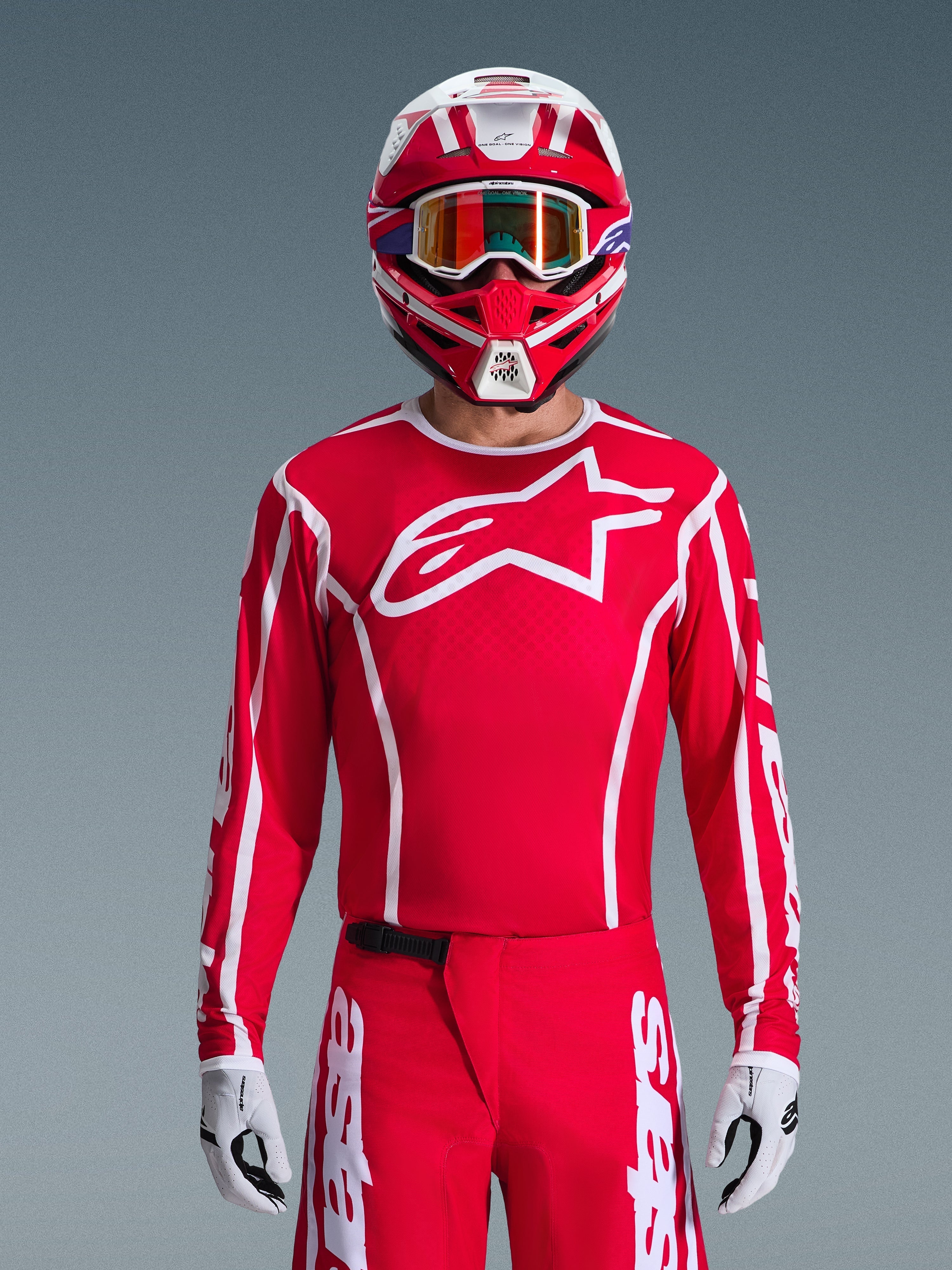 Alpinestars 2026 Fluid Apex Jersey, Motocross Jersey, Red and White, worn by a rider with a matching red and white helmet and orange goggles, featuring a prominent white logo on the chest, athletic fit, part of a coordinated off-road racing gear set