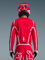 Rückansicht eines Motocross-Fahrers im Alpinestars 2026 Fluid Apex Trikot in Rot und Weiß, mit geometrischen weißen Mustern, kombiniert mit passender Motocross-Hose und einem roten Helm, komplette Rennausrüstung für Offroad-Performance.