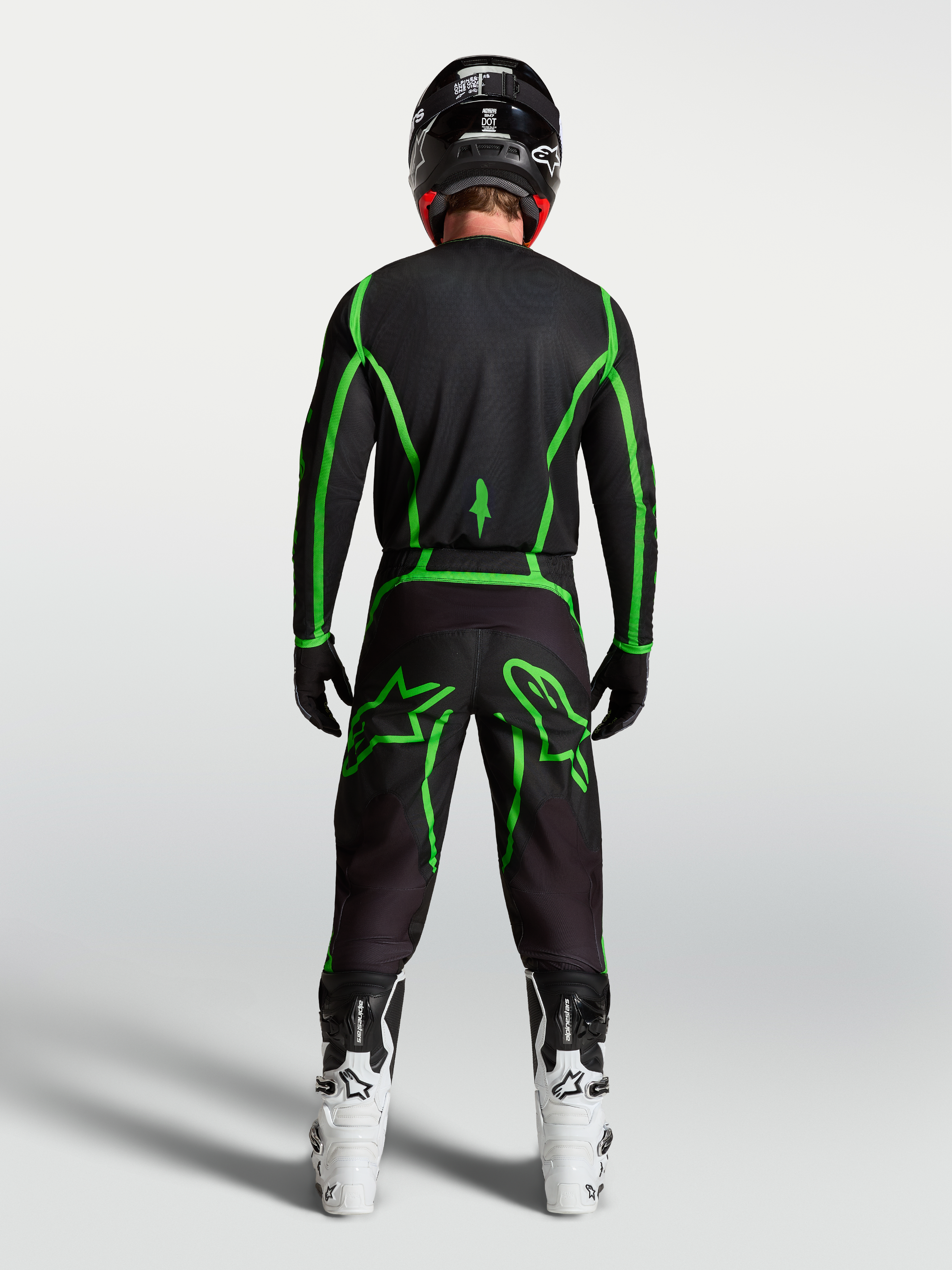 Alpinestars Fluid Apex V2 Hose, Motocross-Hose in Schwarz und Fluo-Grün, Rückansicht am Fahrer mit weißen Motocross-Stiefeln.