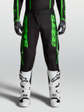 Alpinestars Fluid Apex V2 Hose, Herren Motocross-Hose in Schwarz und Grün mit verstärkten Knien und weißen Stiefeln.