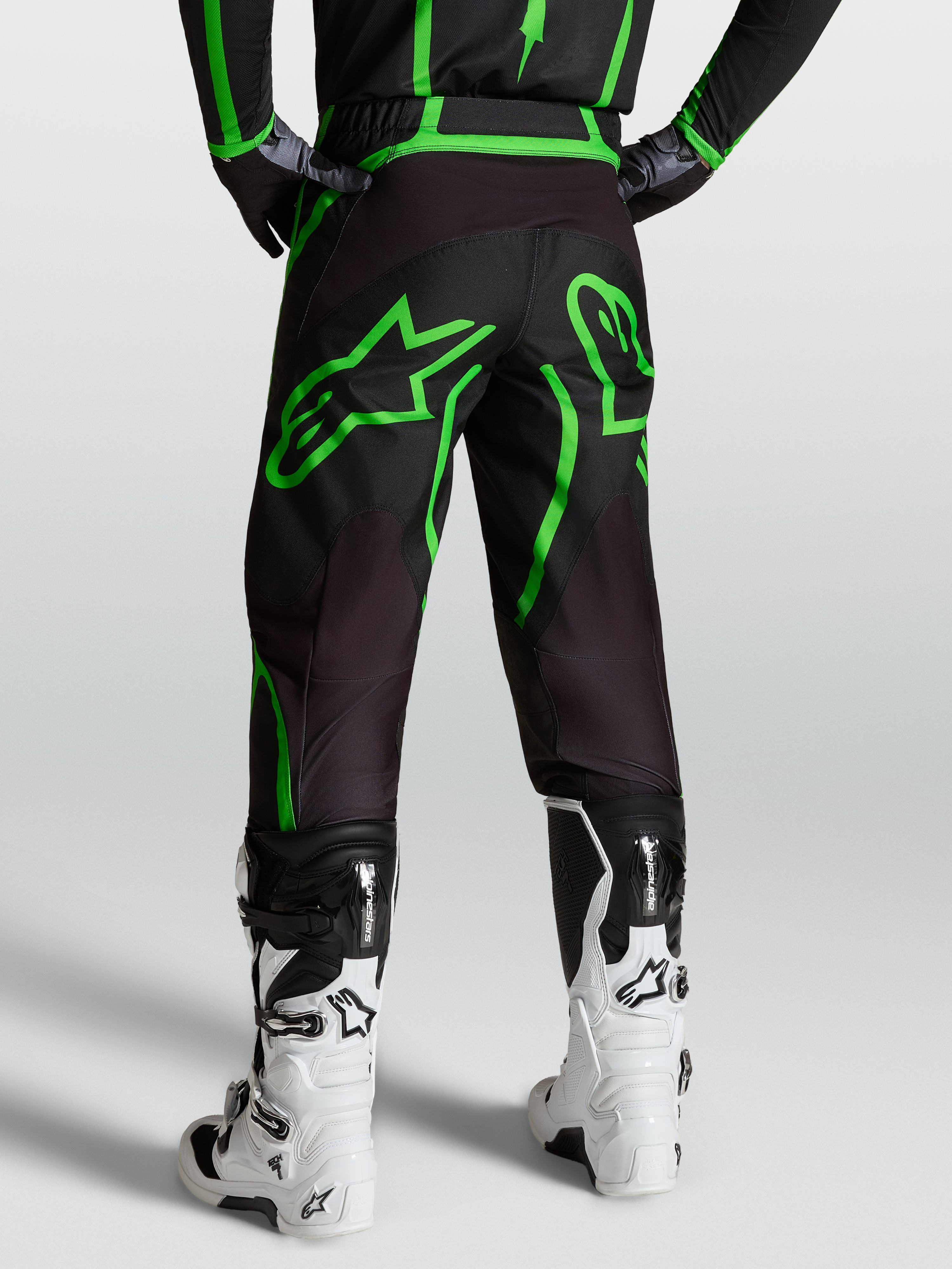 Alpinestars Fluid Apex V2 Hose, Motocross- und Offroad-Hose für Herren, Schwarz und Fluogrün, Rückansicht am Model mit weißen Tech 7 Stiefeln