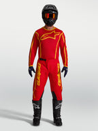 Alpinestars Fluid Apex V2 Trikot und Gear Set, Motocross-Bekleidung in Rot und Gold, Model in kompletter Rennausrüstung.