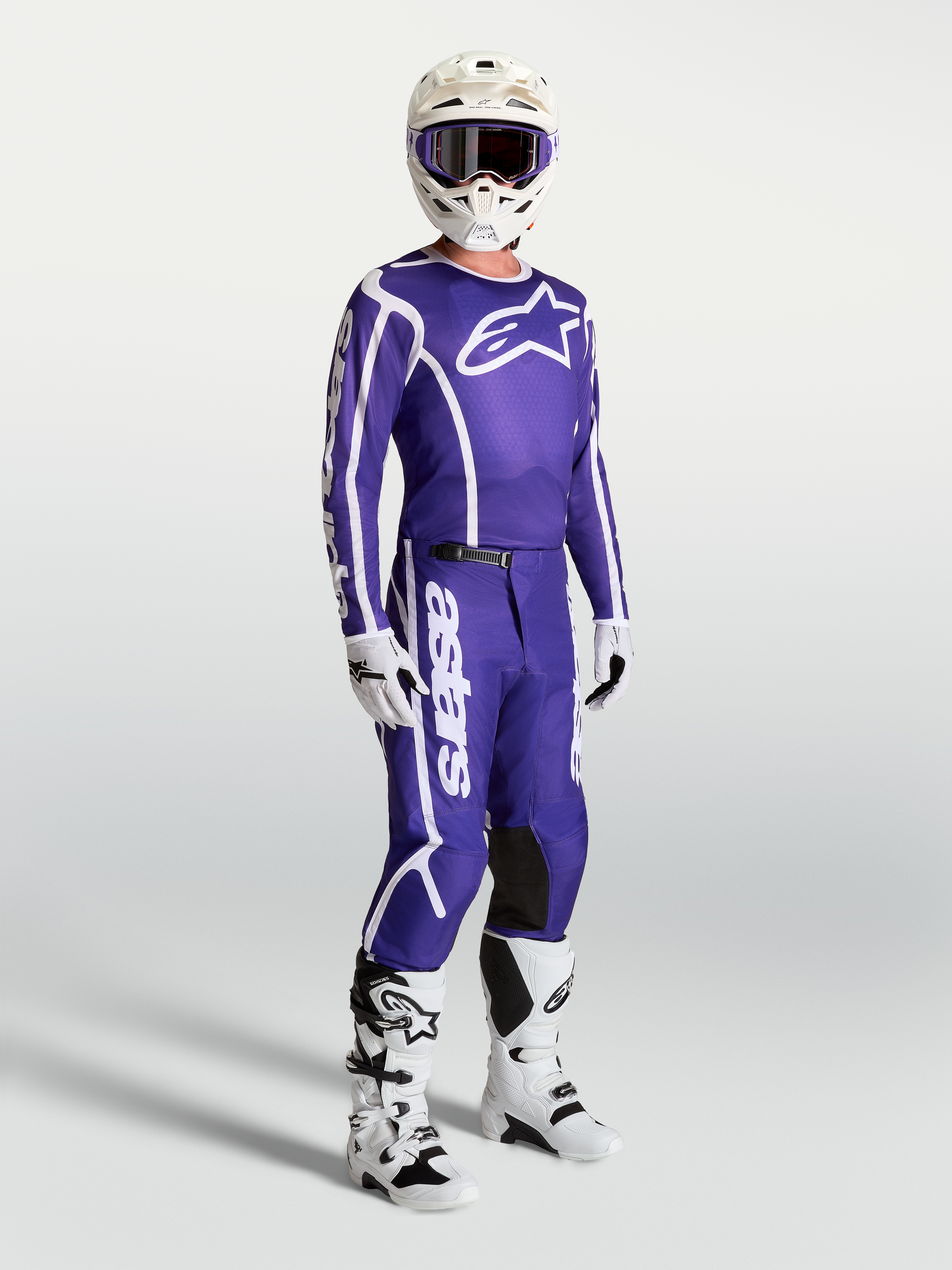 Alpinestars Fluid Apex V2 Trikot und Hose, Motocross-Set in Blau und Weiß, getragen mit weißen Stiefeln und Helm.