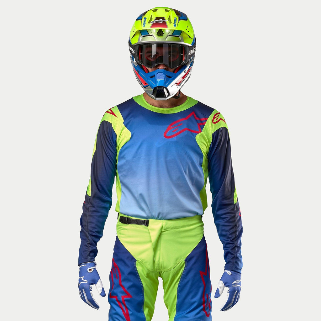 Alpinestars 2024 Racer Hoen Jersey, Motocross Jersey, Yellow Fluo and Blue Night Navy, front view on a rider with matching helmet and gear, featuring a large red logo on the chest and breathable mesh panels.