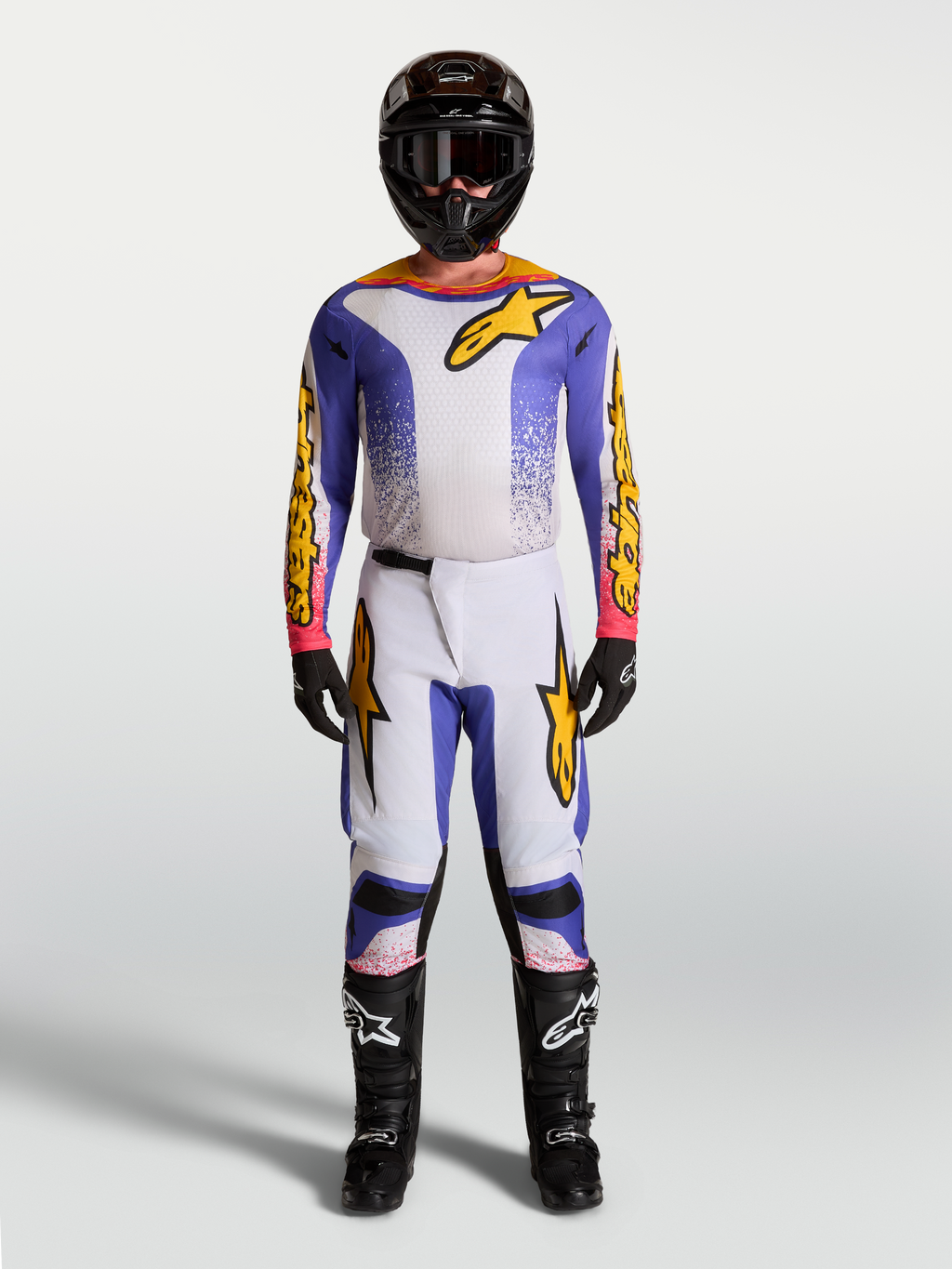 Alpinestars Fluid Drag Motocross-Set, Trikot und Hose für Herren, Lila, Blau und Gold, sportliche Passform für MX-Performance, getragen mit Helm und Stiefeln.