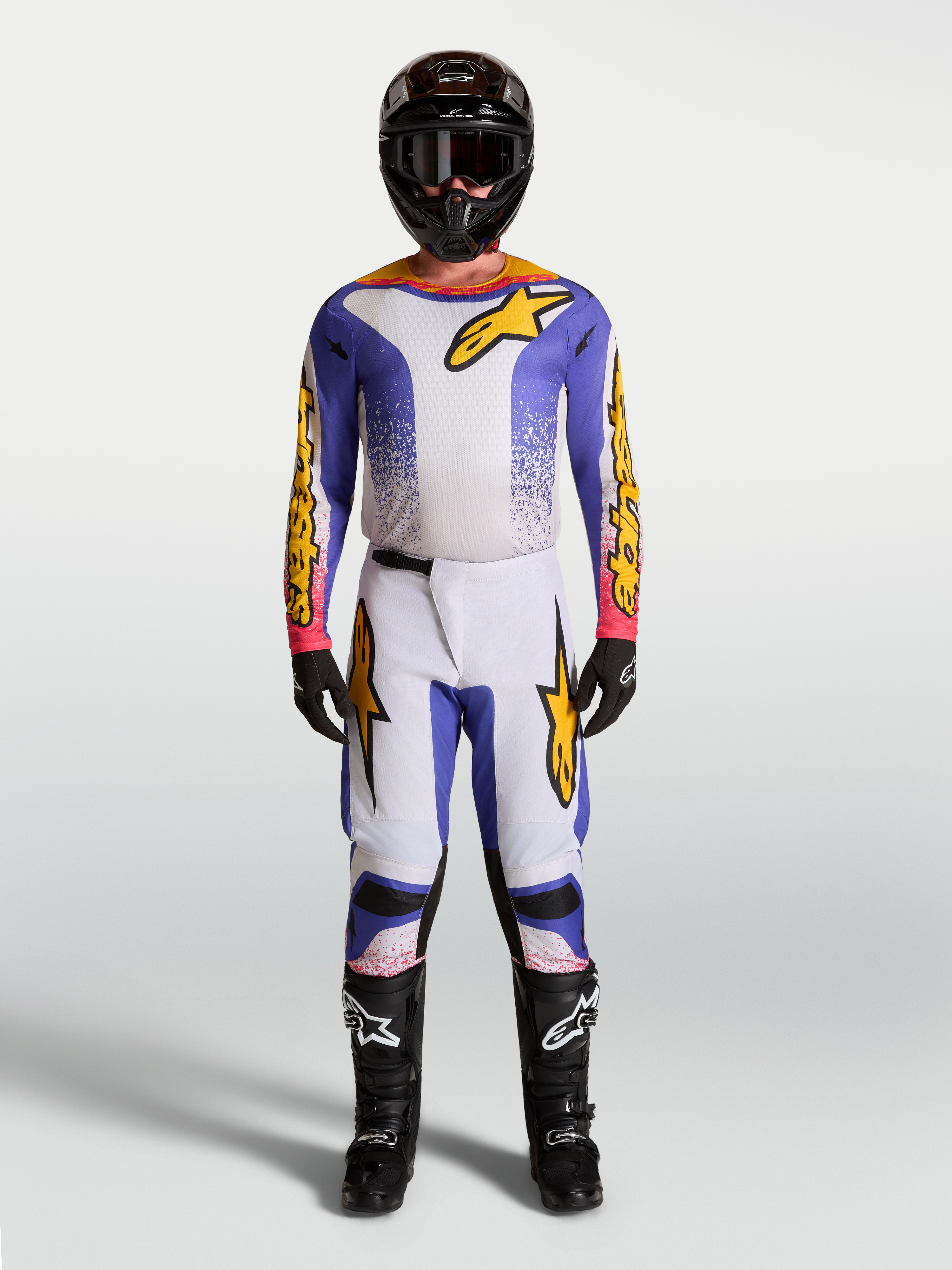 Alpinestars Fluid Drag Motocross-Set, Trikot und Hose für Herren, Lila, Blau und Gold, sportliche Passform für MX-Performance, getragen mit Helm und Stiefeln.