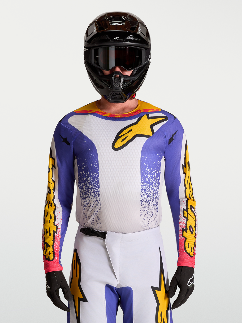 Alpinestars Fluid Drag Trikot, Motocross-Trikot für Herren in Blau Iris und Gold, feuchtigkeitsableitendes Gewebe, sportlicher Schnitt, getragen mit MX-Helm und Schutzbrille.