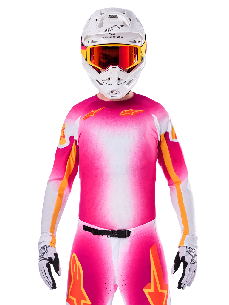 Motocross-Fahrer im Alpinestars Limited Edition Supertech AFD MIG Jersey, Pink-Fluo-Wei&szlig;er Farbverlauf mit orangefarbenen Stern-Logos, passende Hose, wei&szlig;er Helm und rot get&ouml;nte Brille, Elite-Offroad-Rennausr&uuml;stung