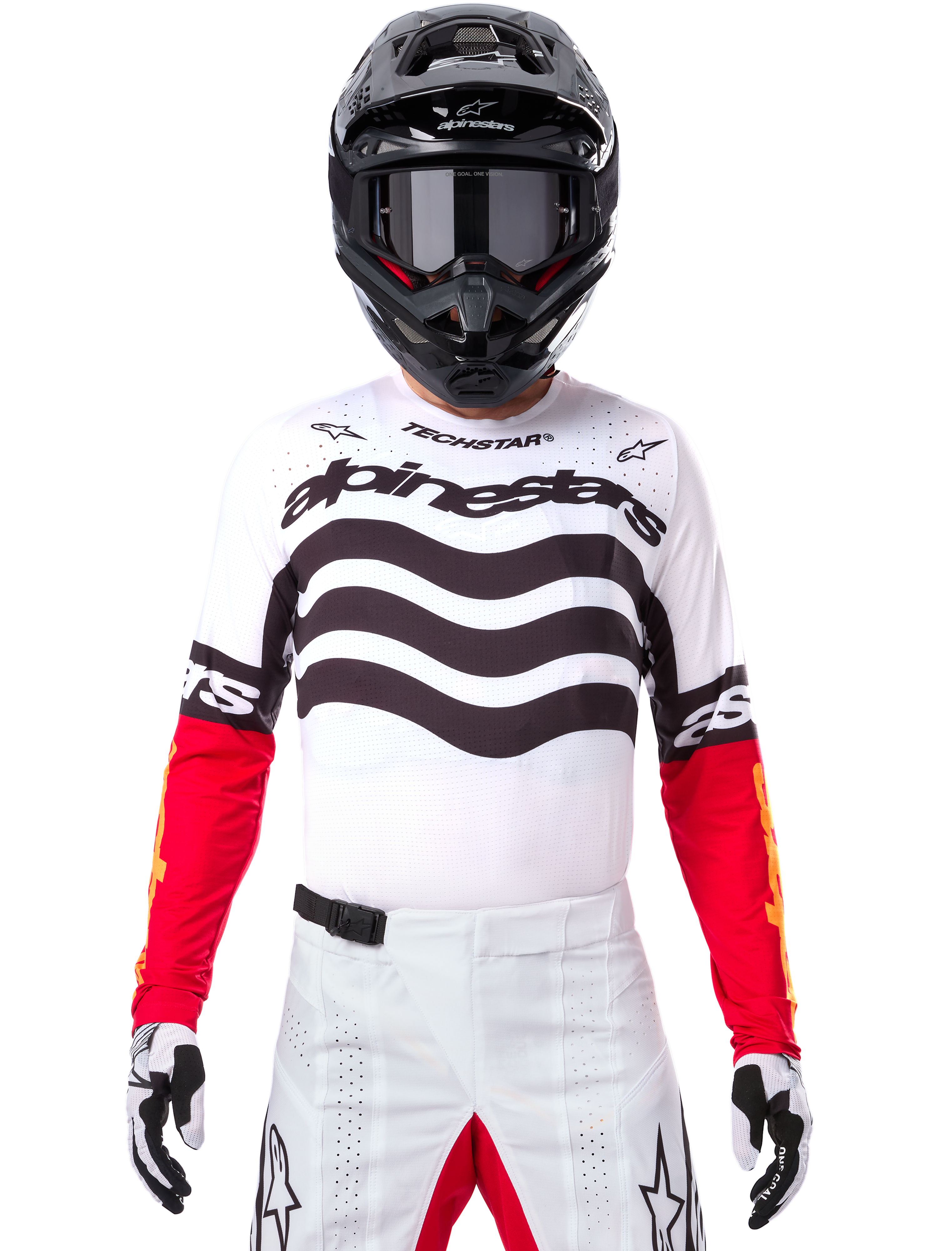 Motocross-Fahrer in kompletter Rennausrüstung, Limited Edition Techstar Deep Trikot in Weiß und Schwarz mit roten Ärmeln, wellenförmige Grafiken und markantes Alpinestars-Branding, weiße Motocross-Hose, schwarzer Helm und Brille, abgestimmtes Outfit für Offroad-Rennen