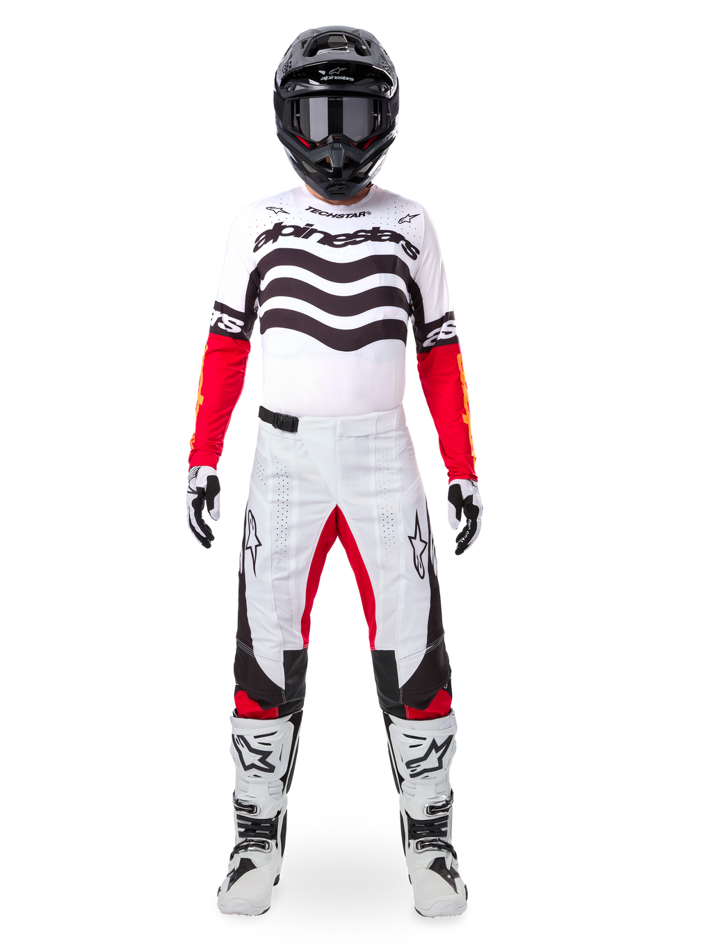 Motocross-Fahrer im Alpinestars Limited Edition Techstar Deep Trikot in Weiß, Schwarz und Rot mit wellenförmigen Grafiken auf der Brust, kombiniert mit einer passenden weiß-roten Hose, einem schwarzen Helm und weißen Rennstiefeln, komplette professionelle Offroad-Ausrüstung.