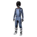 Motocross rider wearing complete racing gear, Alpinestars 2024 Fluid Lurv Jersey in light blue and black, matching light blue pants with black panels, white and black boots, black gloves, and black helmet with goggles, coordinated outfit for off-road racing