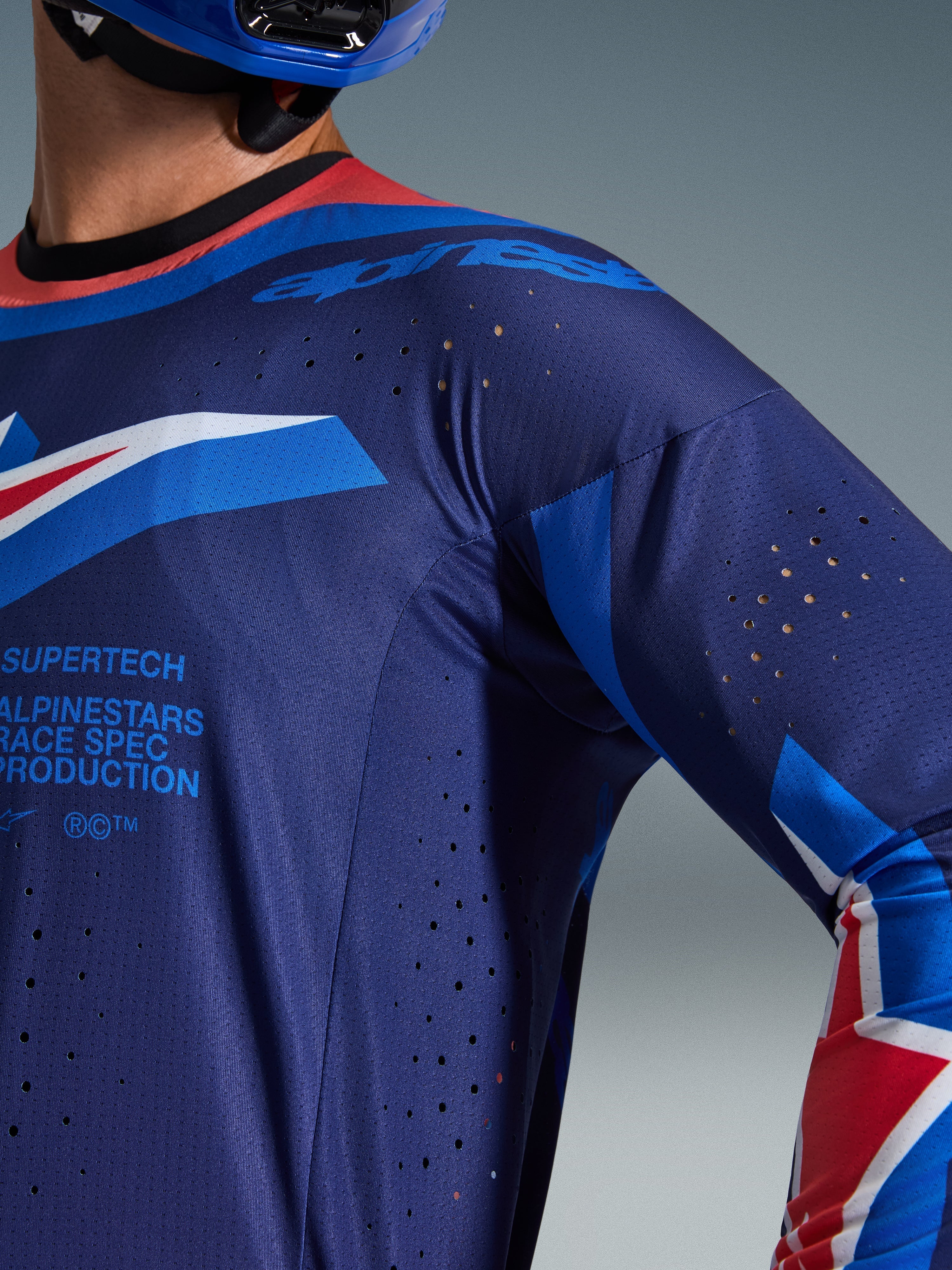 Alpinestars 2026 Supertech Vista Jersey, Motocross Jersey, Dark Navy with Hot Coral and Cobalt accents, close-up showing laser-cut ventilation perforations and breathable mesh texture, features 'Supertech Race Spec' branding, pro-level racing gear