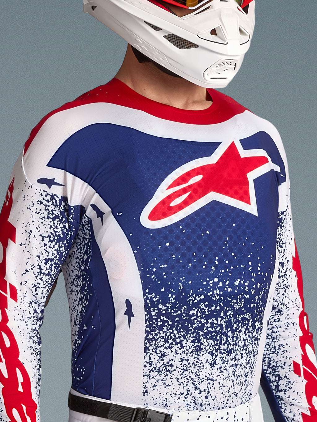Alpinestars Techstar Unity Trikot Limited Edition, blau-weißes Motocross-Trikot für Herren mit rotem Stern-Logo und weißem Helm.