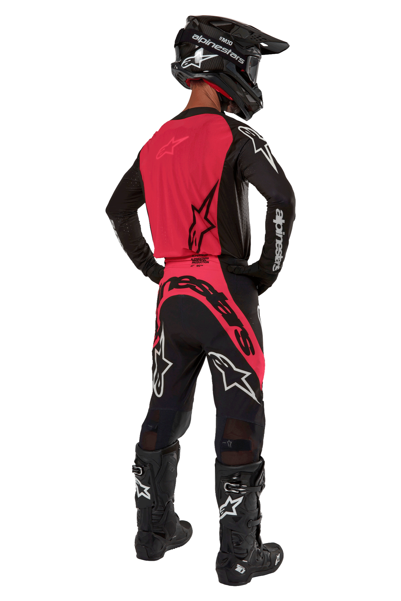 Motocross-Fahrer von hinten im 2024 Supertech Ward Jersey in Black Red Berry, mit leuchtend roter Rückenpartie und schwarzen Ärmeln mit weißem Alpinestars-Logo, kombiniert mit passender Motocross-Hose, schwarzen Tech 10 Stiefeln und einem schwarzen Carbonhelm, professionelles Rennsport-Ausrüstungsset.