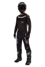 Motocross-Fahrer in kompletter Rennausrüstung, 2024 Supertech Ward Trikot in Schwarz Rot Berry, schwarzes Trikot mit weißem Alpinestars-Branding, schwarze Hose mit roten Seitenbahnen und großen weißen Astars-Logos, schwarzer Helm, Handschuhe und Stiefel, abgestimmtes Profi-Outfit für den Offroad-Rennsport