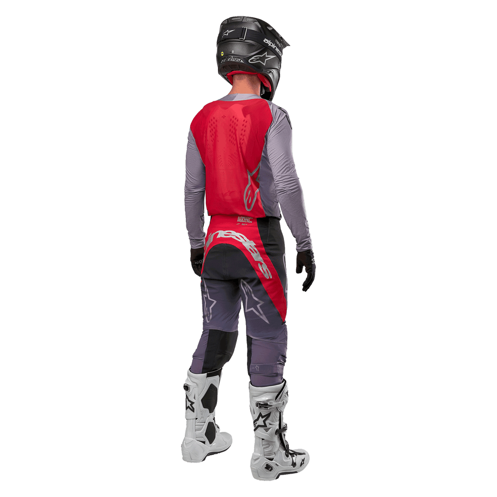 Alpinestars 2024 Supertech Dade Trikot, Motocross-Trikot, Iron Red Berry und Grau, Rückansicht eines Fahrers, mit einem roten Rückenteil, grauem Logo und grauen Ärmeln, getragen mit passender grau-roter Renn-Hose, weißen Stiefeln und einem schwarzen Helm, professionelle Offroad-Ausrüstung.