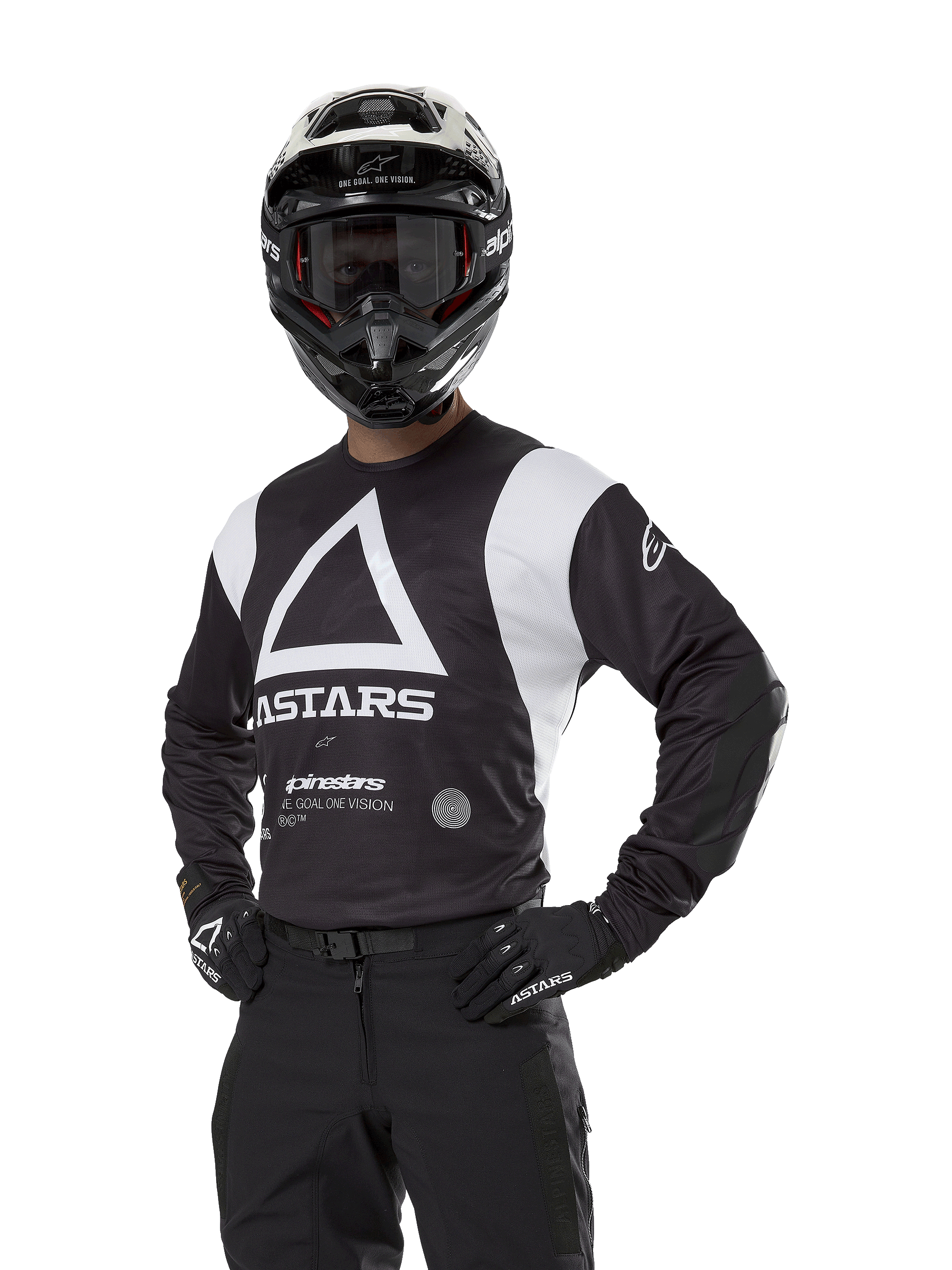Alpinestars Techdura Jersey, Motocross-Trikot, Schwarz und Weiß, getragen mit passendem Helm und Handschuhen, Pose mit den Händen auf den Hüften vor weißem Hintergrund, mit großem Dreieck-A-Logo und ASTARS-Branding
